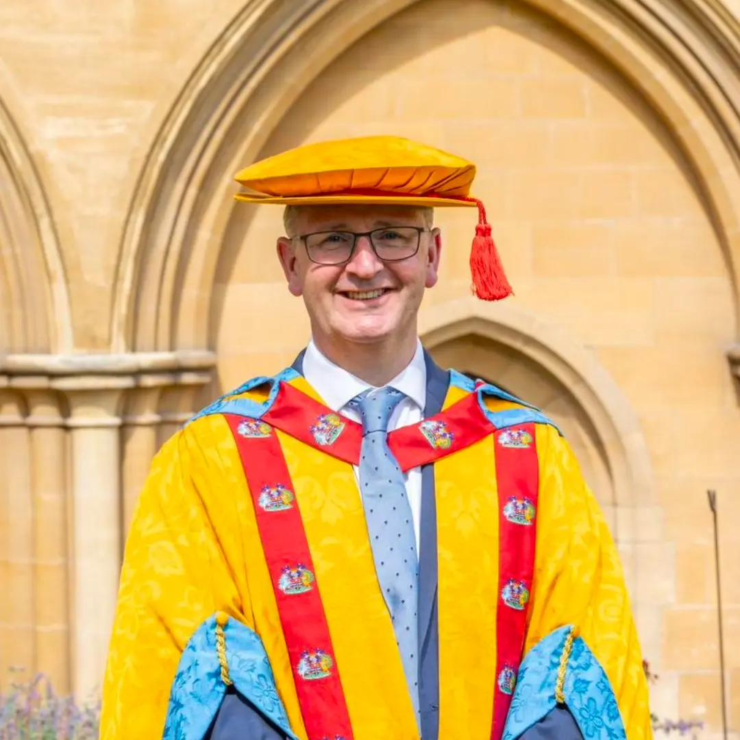Principal Simon Cook receiving Honorary Doctorate smiling at the camera